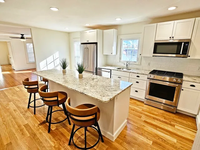 a kitchen with granite countertop a table chairs microwave and cabinets