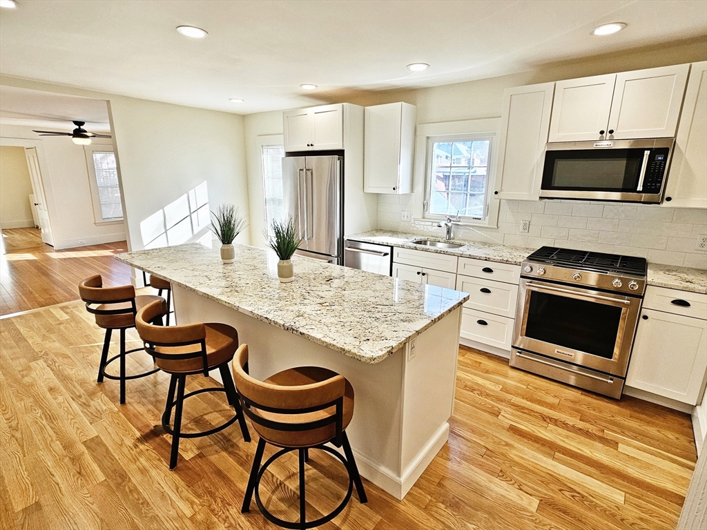 a kitchen with granite countertop a table chairs microwave and cabinets