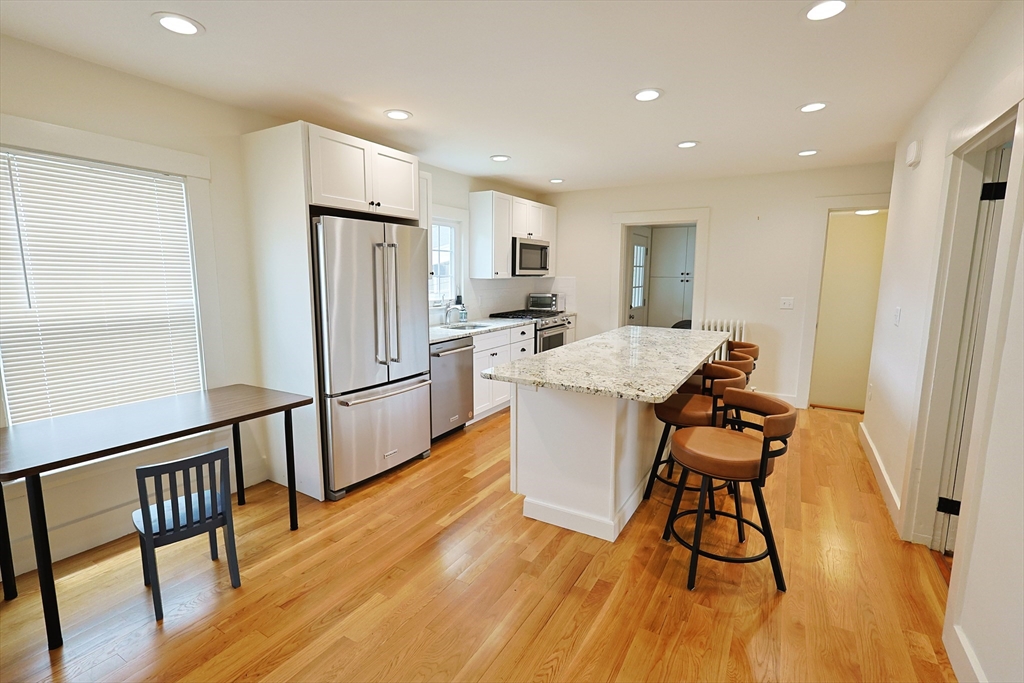 11 Channing Street, Unit 2 Newton, MA 02458 - Photo 30 of 33 a kitchen with stainless steel appliances a dining table chairs and wooden floors