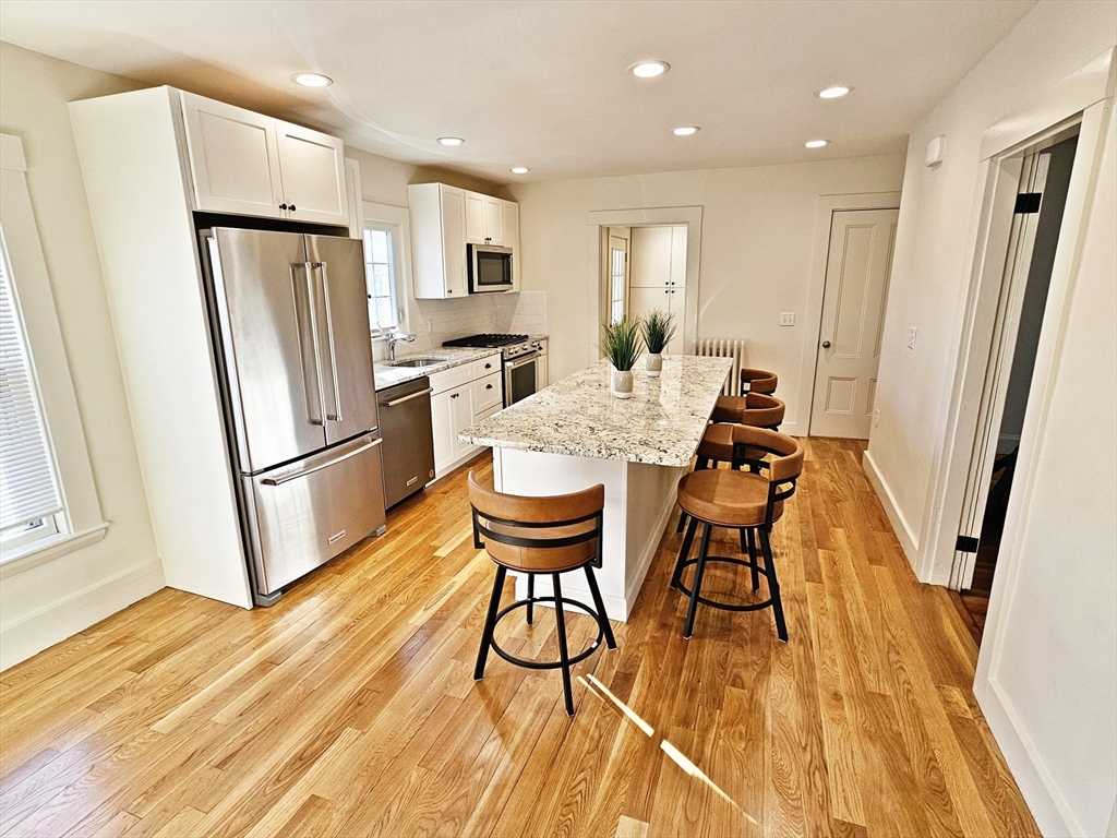 11 Channing Street, Unit 2 Newton, MA 02458 - Photo 3 of 33 a kitchen with stainless steel appliances a refrigerator a sink dishwasher and a stove with wooden floor