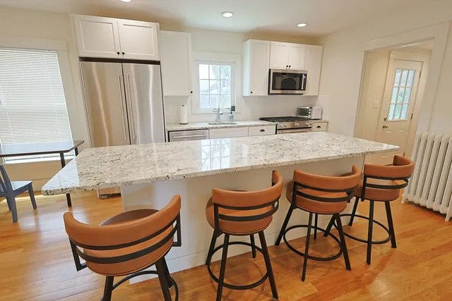 a kitchen with stainless steel appliances granite countertop a table chairs and a refrigerator