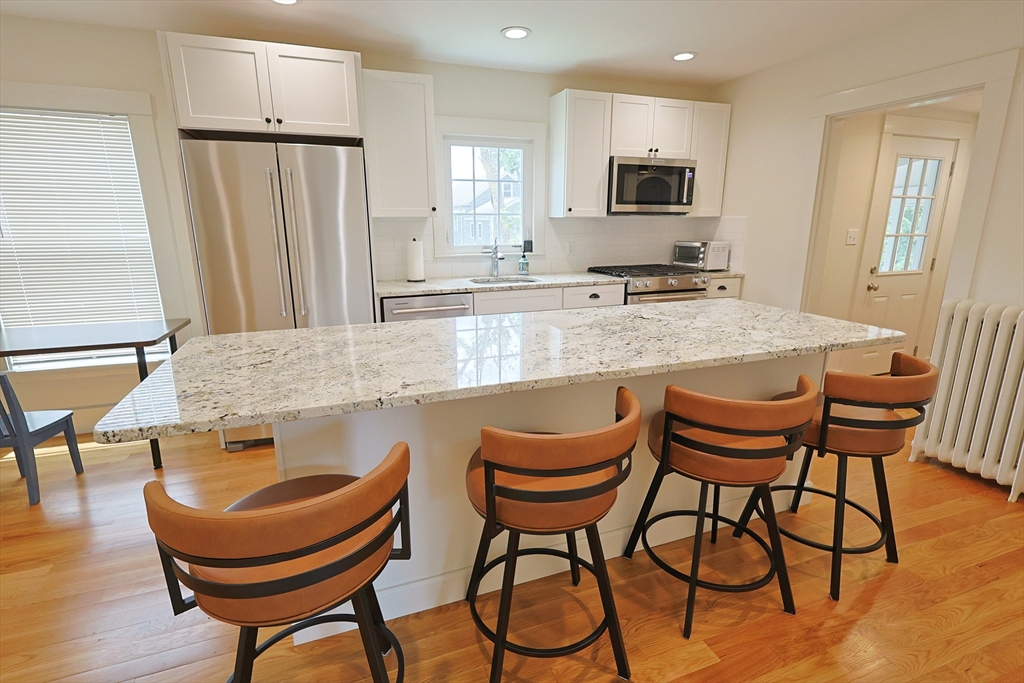 11 Channing Street, Unit 2 Newton, MA 02458 - Photo 33 of 33 a kitchen with stainless steel appliances granite countertop a table chairs and a refrigerator