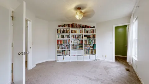 a view of an empty room with a window and cabinet