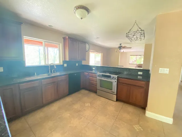 a open kitchen with granite countertop a sink dishwasher stove and cabinets