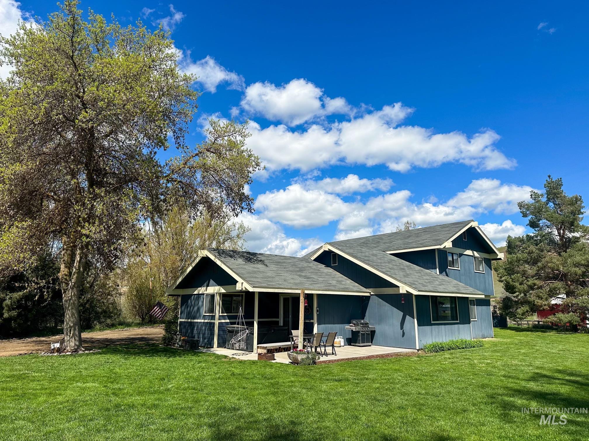 Back of house featuring a yard, a patio, roof with shingles, and a sunroom
