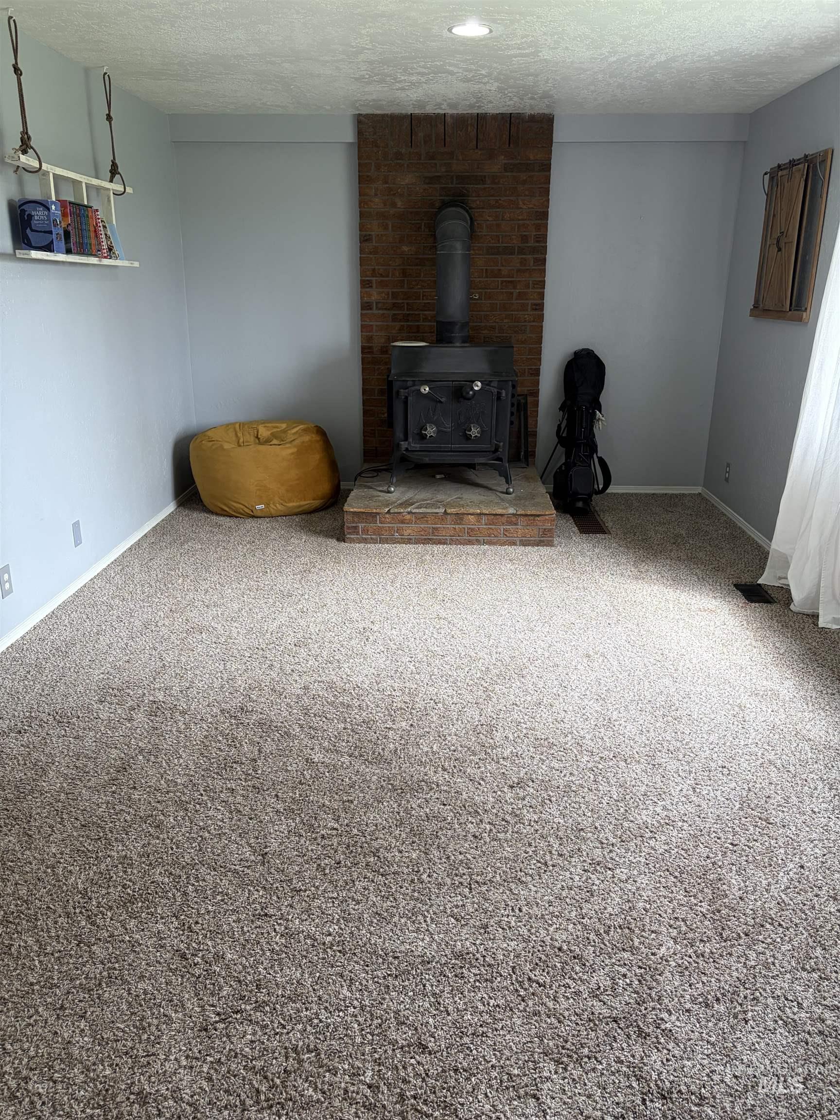 1452 Weiser River Road Weiser, ID 83672 - Photo 11 of 40 Living area with a textured ceiling, a wood stove, and carpet