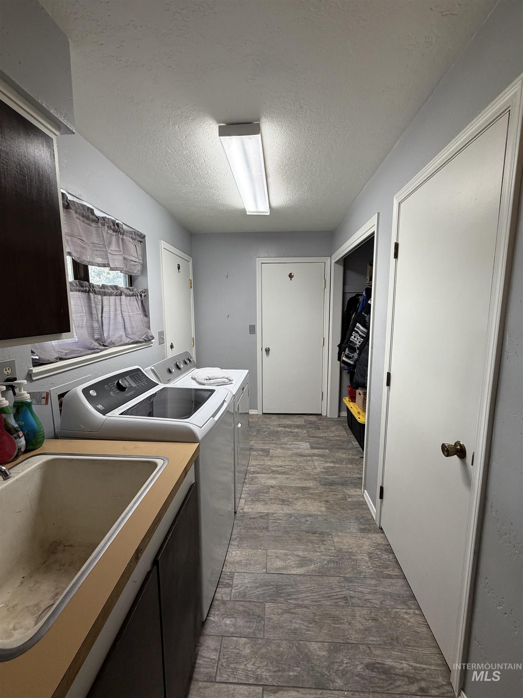 1452 Weiser River Road Weiser, ID 83672 - Photo 14 of 40 Laundry room with a textured ceiling, washer and clothes dryer, and dark wood-style floors