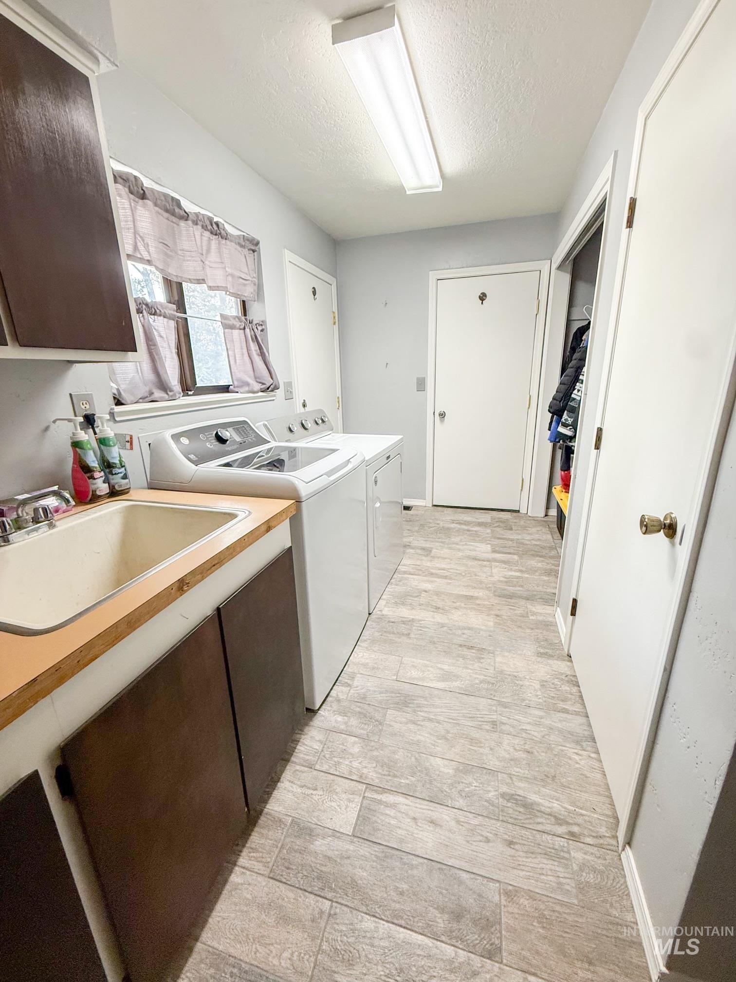 1452 Weiser River Road Weiser, ID 83672 - Photo 14 of 38 Dedicated laundry area featuring wood-finish flooring, a utility sink with a wood countertop, and ample storage cabinetry