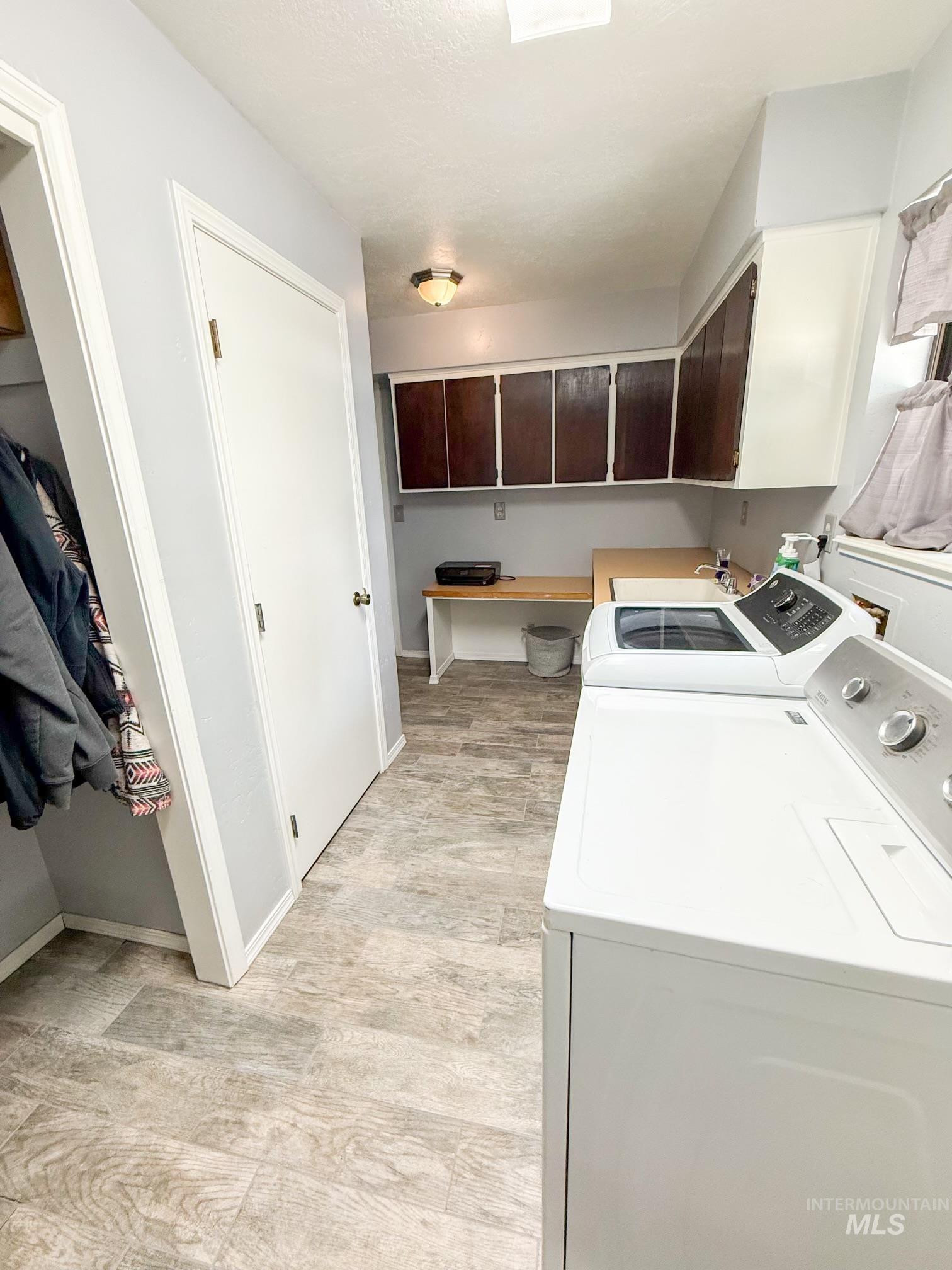1452 Weiser River Road Weiser, ID 83672 - Photo 15 of 38 Laundry room featuring wood-finish flooring, built-in cabinetry, an integrated sink, and an expansive countertop workspace