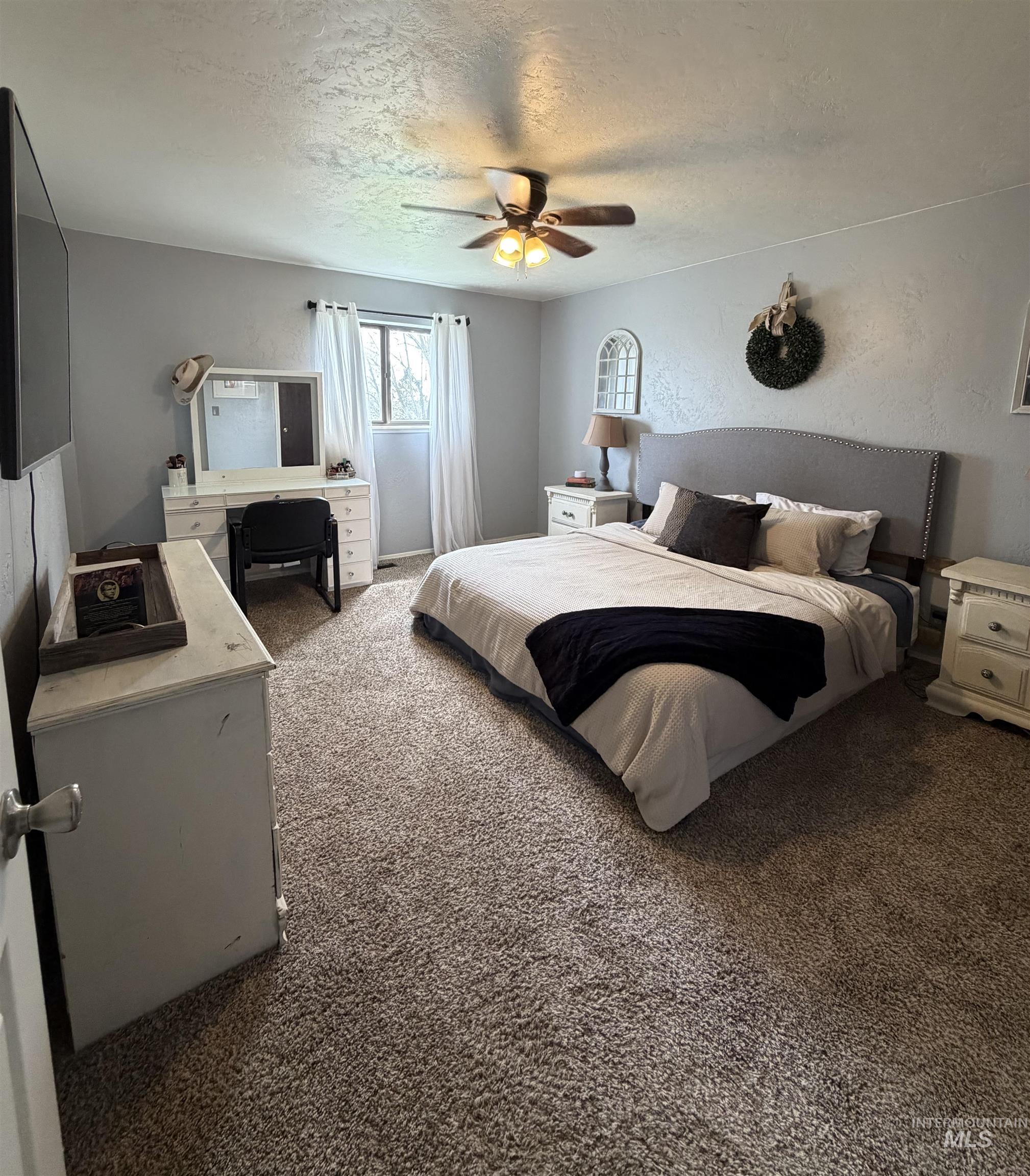 1452 Weiser River Road Weiser, ID 83672 - Photo 18 of 40 Bedroom with dark carpet, a ceiling fan, a textured ceiling, and a textured wall