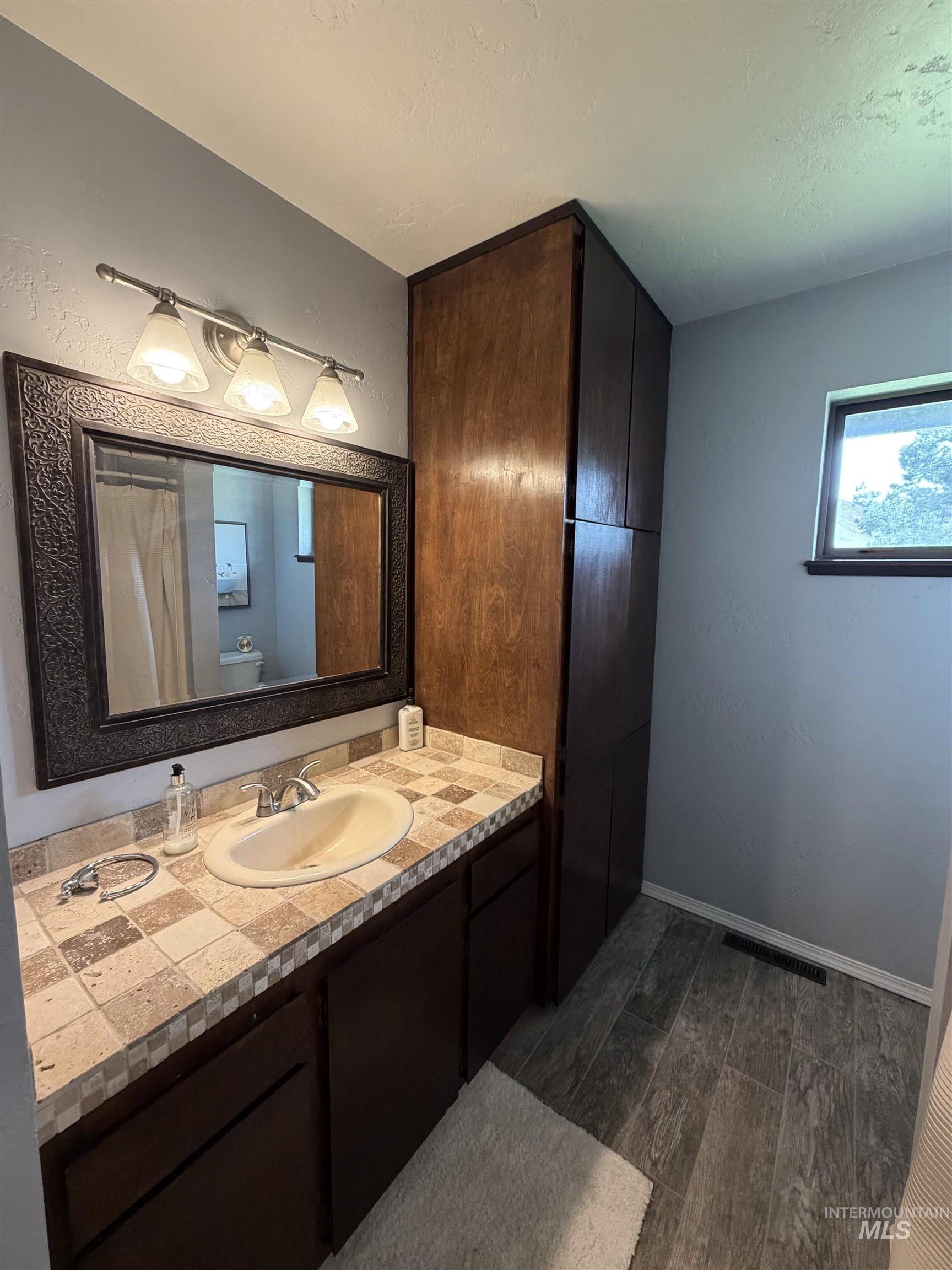 1452 Weiser River Road Weiser, ID 83672 - Photo 24 of 40 Full bathroom with vanity, wood tiled floors, curtained shower, and a textured ceiling