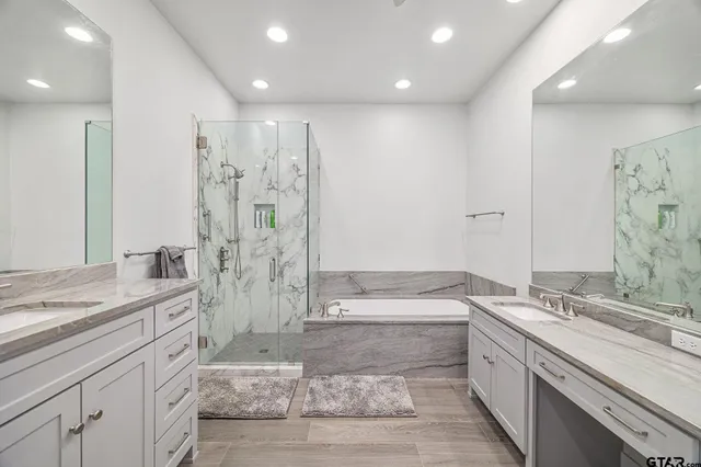a large bathroom with a granite countertop sink a toilet a large mirror a shower and bathtub