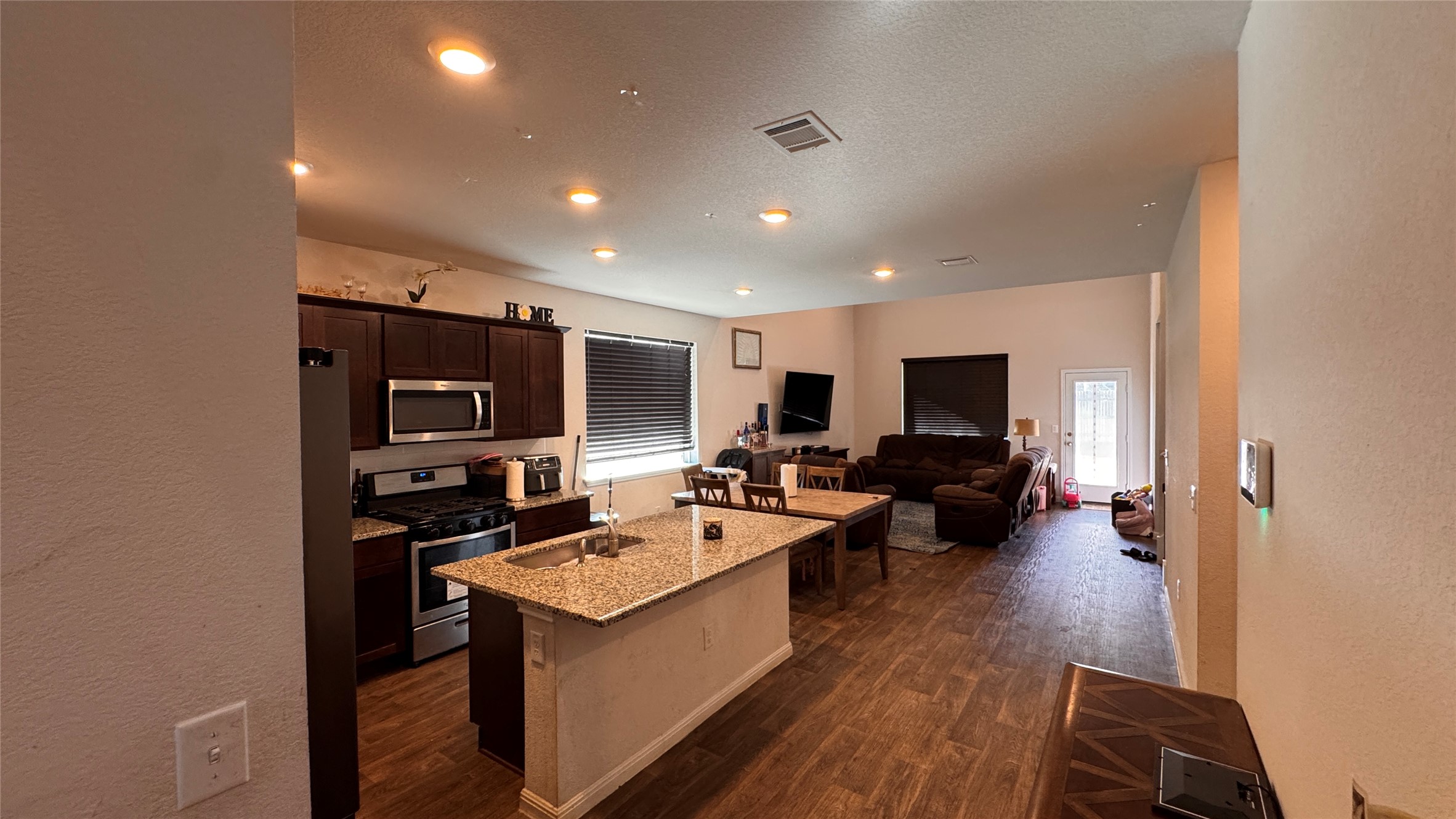 201 Finley Rae Drive Georgetown, TX 78626 - Photo 6 of 17 An open-concept living space integrates a well-appointed kitchen with dining and lounge areas, featuring rich wood-look flooring.
