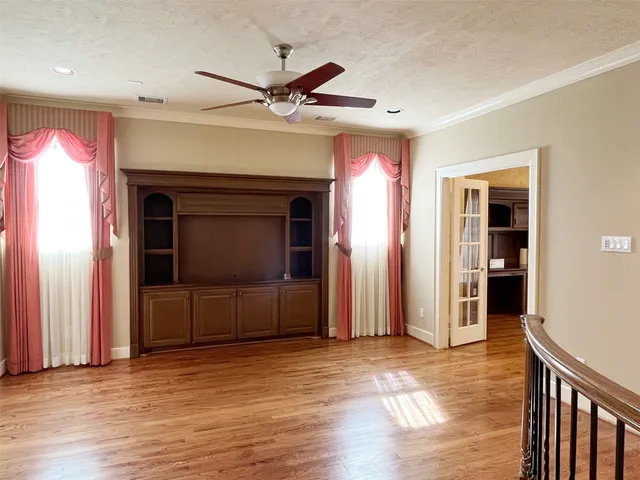 an empty room with wooden floor closet and windows