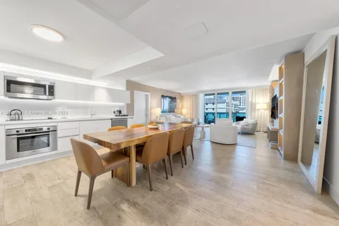 a living room with stainless steel appliances furniture a rug and a kitchen view