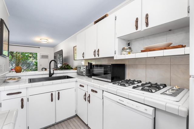 a kitchen with kitchen island a sink appliances cabinets and a counter top space