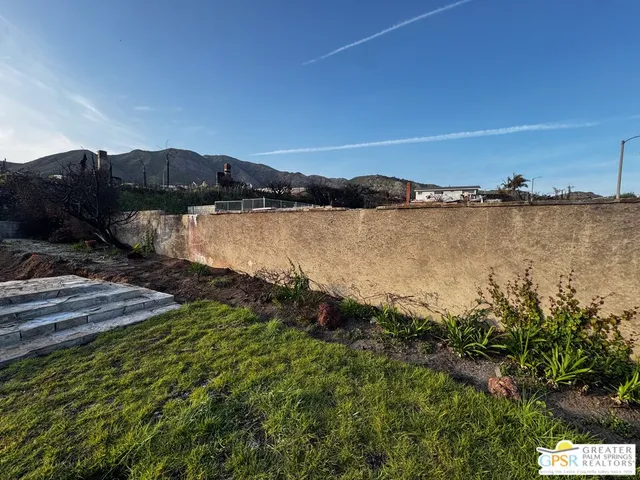 a view of a dry yard with wooden fence