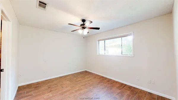 a view of an empty room with chandelier fan and wooden floor
