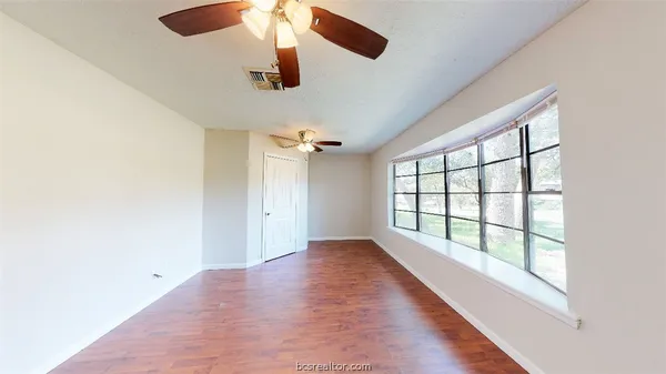 an empty room with wooden floor and windows
