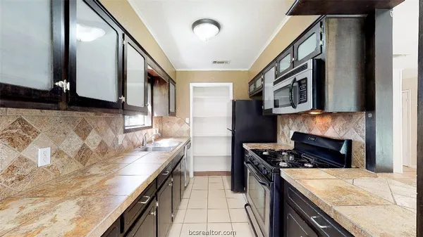 a kitchen with stainless steel appliances granite countertop a stove a sink and a microwave