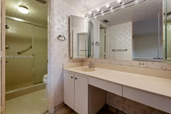 a bathroom with a sink and mirror with shower