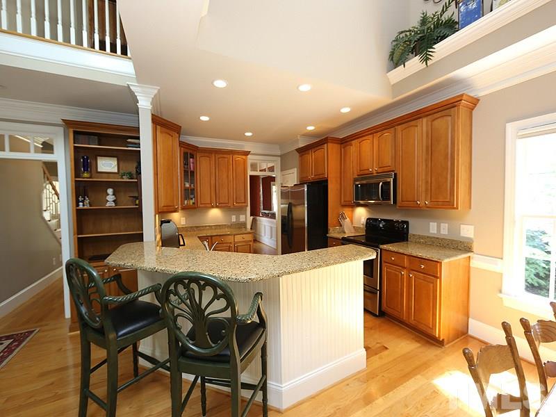 204 Okamato Street Raleigh, NC 27603 - Photo 5 of 25 a kitchen with stainless steel appliances kitchen island granite countertop a table chairs and a refrigerator