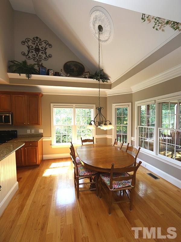 204 Okamato Street Raleigh, NC 27603 - Photo 6 of 25 a dining room with wooden floor a chandelier a wooden table and chairs