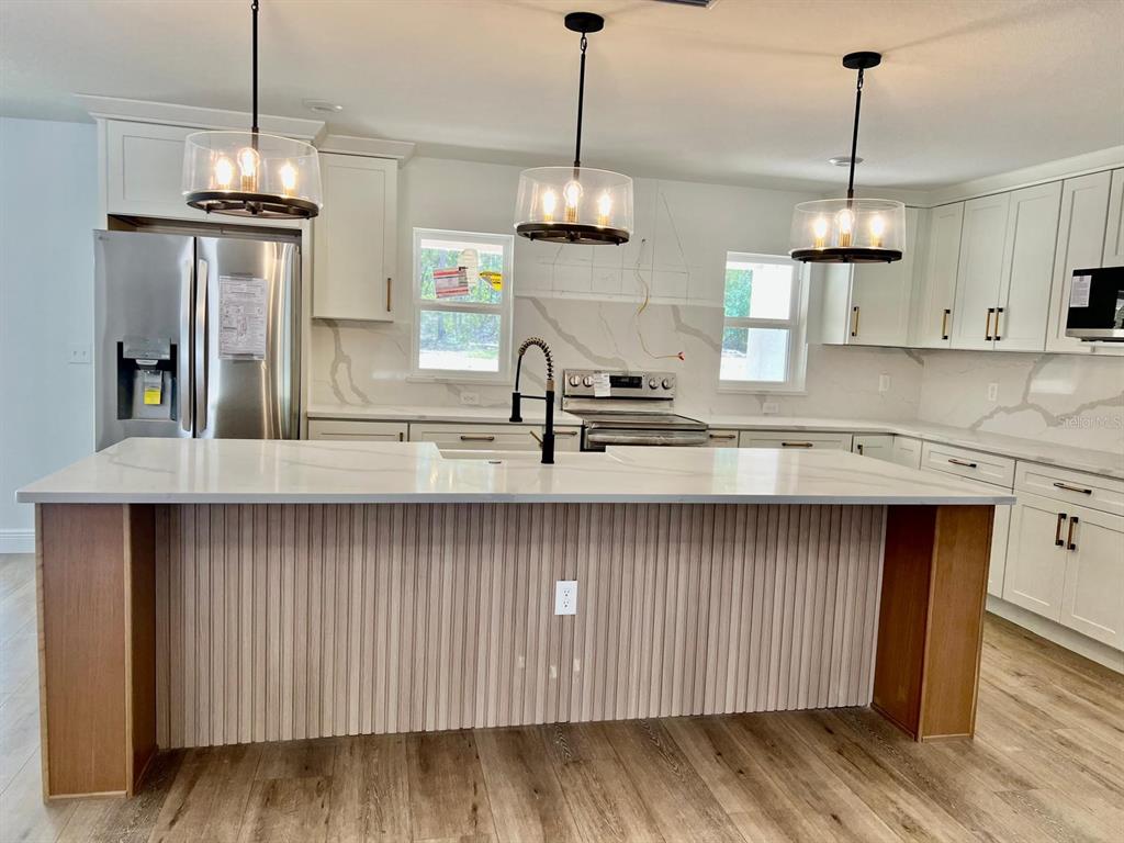 13322 Southwest 66th Street Ocala, FL 34481 - Photo 4 of 15 a kitchen with stainless steel appliances granite countertop wooden cabinets a dining table and chairs