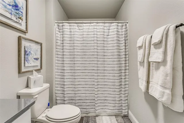a bathroom with a toilet and a shower curtain