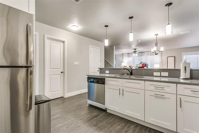 a kitchen with stainless steel appliances granite countertop a refrigerator a sink and white cabinets