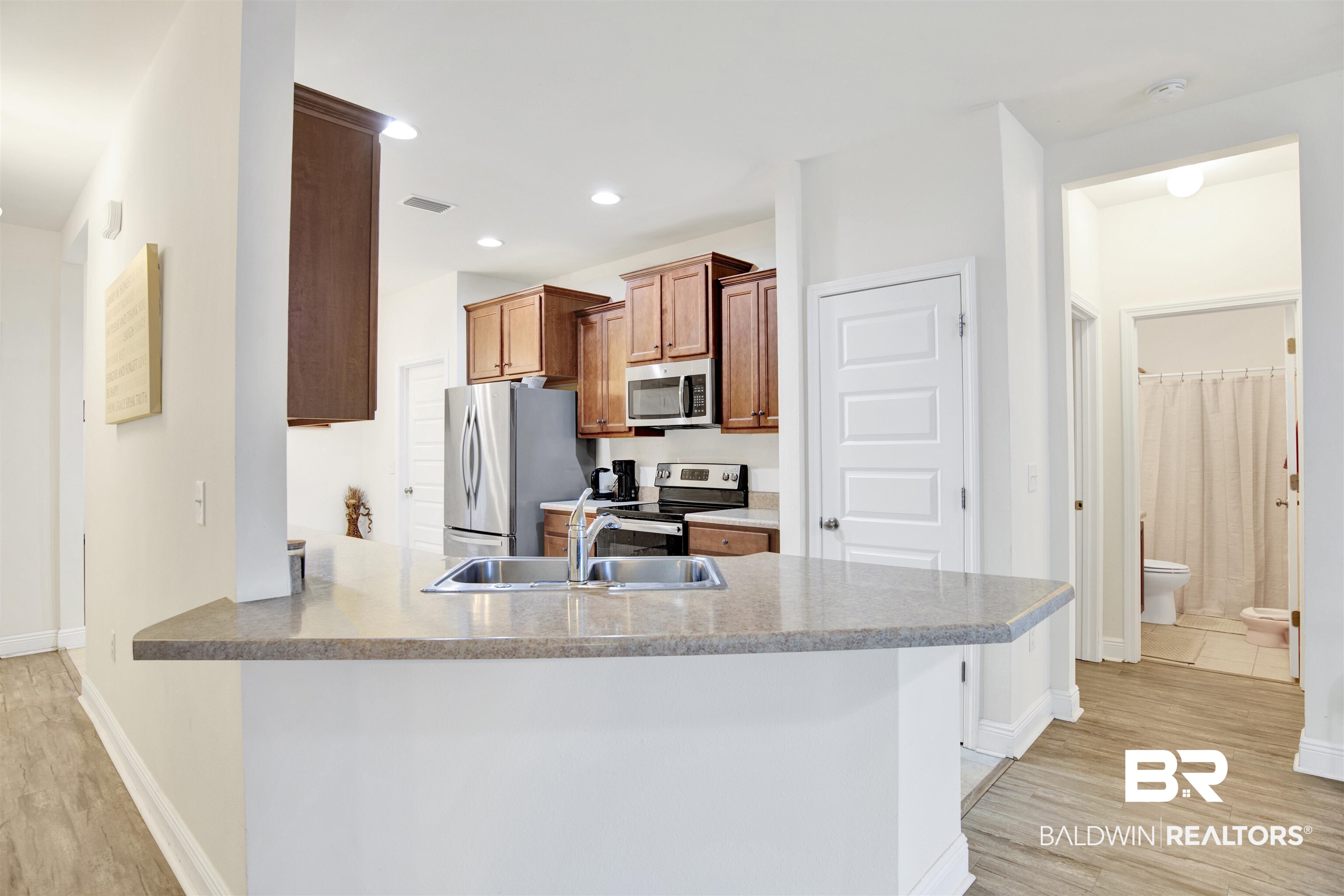 1468 Surrey Loop Foley, AL 36535 - Photo 12 of 28 Kitchen featuring stainless steel appliances, light wood finished floors, a sink, baseboards, and a peninsula