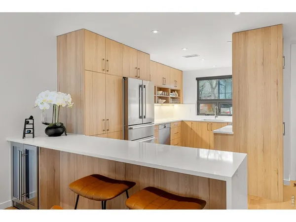 a kitchen with stainless steel appliances granite countertop a refrigerator a sink dishwasher and wooden cabinets with wooden floor