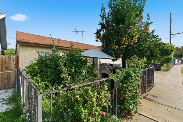 a view of a house with plants and wooden fence