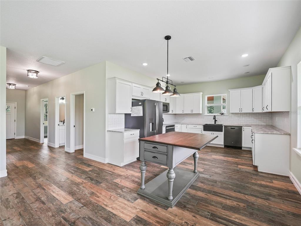 8567 Cr 635 Bushnell Bushnell, FL 33513 - Photo 12 of 46 a room with stainless steel appliances kitchen island granite countertop a refrigerator a stove a sink dishwasher and white cabinets with wooden floor