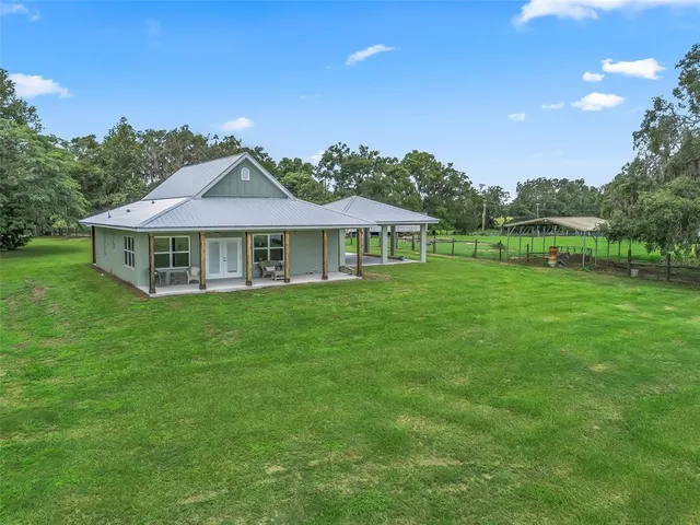 a backyard of a house with large trees and plants