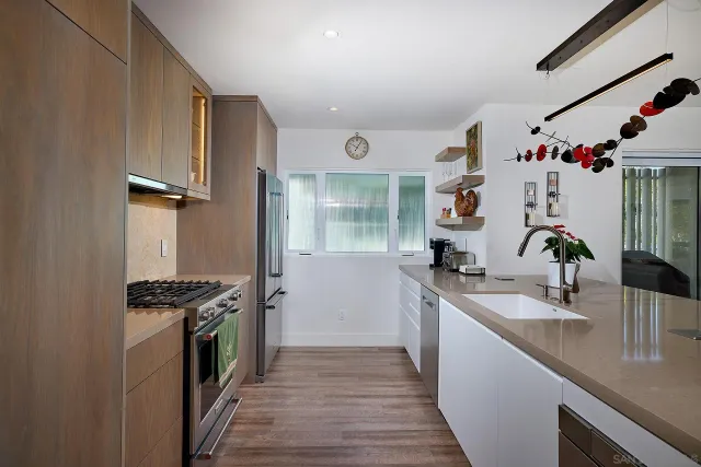 a kitchen with stainless steel appliances granite countertop a stove a refrigerator and a sink with wooden cabinets