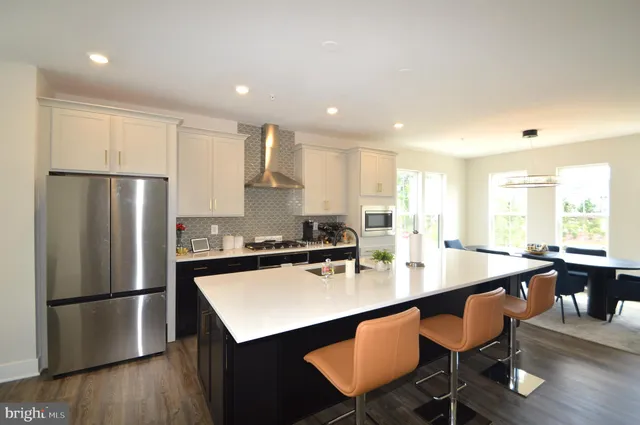 a kitchen with stainless steel appliances a dining table chairs refrigerator and sink