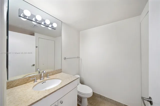 a bathroom with a granite countertop sink a toilet and a mirror