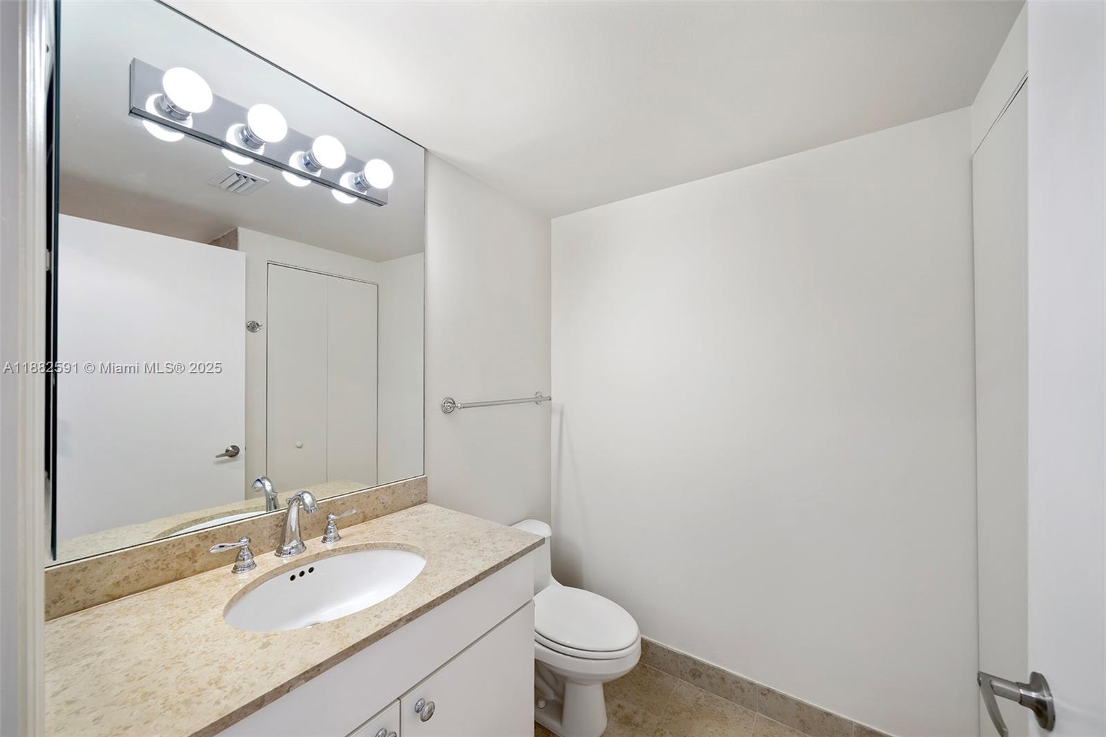 4779 Collins Avenue, Unit 501 Miami Beach, FL 33140 - Photo 26 of 45 a bathroom with a granite countertop sink a toilet and a mirror