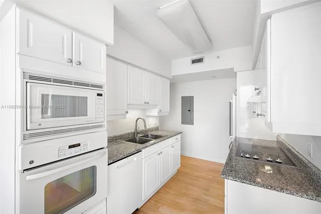 a kitchen with granite countertop white cabinets and white appliances