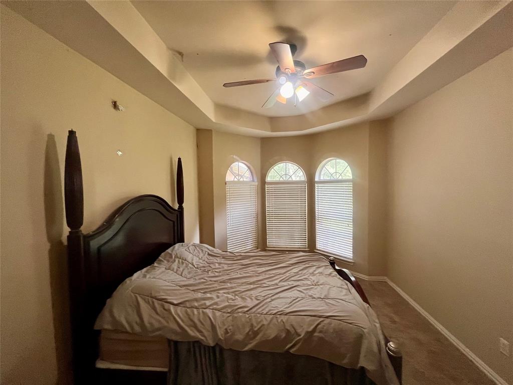 341 Rolling Oaks Ridge Cedar Hill, TX 75104 - Photo 22 of 27 Carpeted bedroom featuring a tray ceiling and a ceiling fan