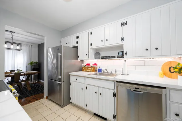 a kitchen with stainless steel appliances a sink a refrigerator and a cabinets
