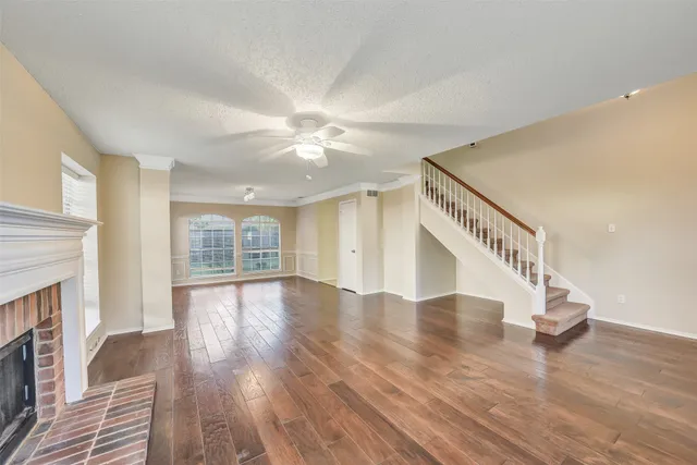 a view of an empty room with wooden floor and a fireplace