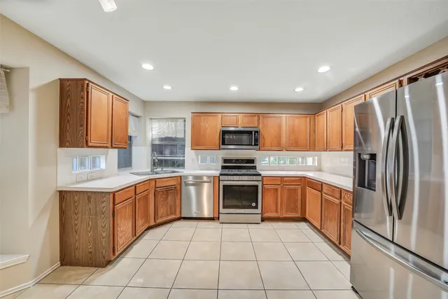 a large kitchen with stainless steel appliances granite countertop a stove top oven a sink dishwasher and a refrigerator