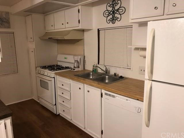 10200 Johnson Road, Unit 44 Phelan, CA 92371 - Photo 5 of 29 a kitchen with stainless steel appliances granite countertop white cabinets and white appliances
