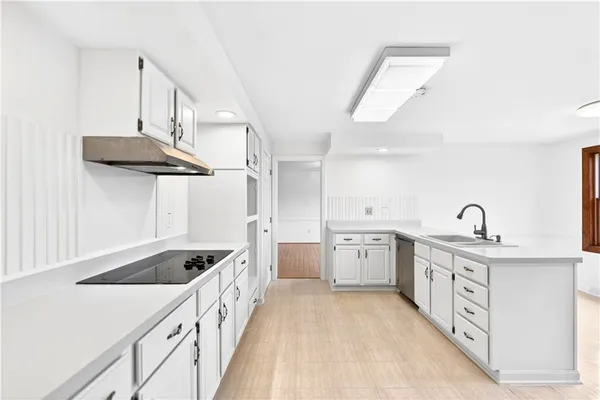 a kitchen with white cabinets a sink dishwasher and a stove with wooden floor