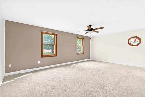 an empty room with windows and ceiling fan