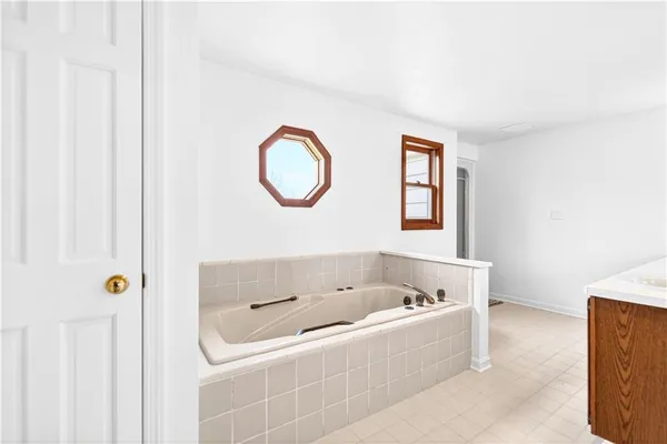 a bathroom with a tub a sink and a window