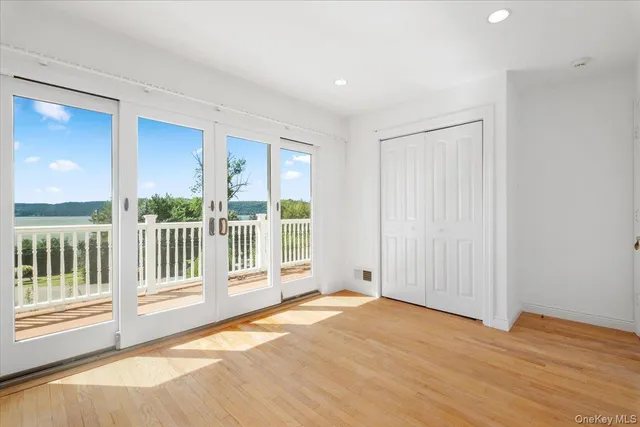 a view of an empty room with wooden floor and windows