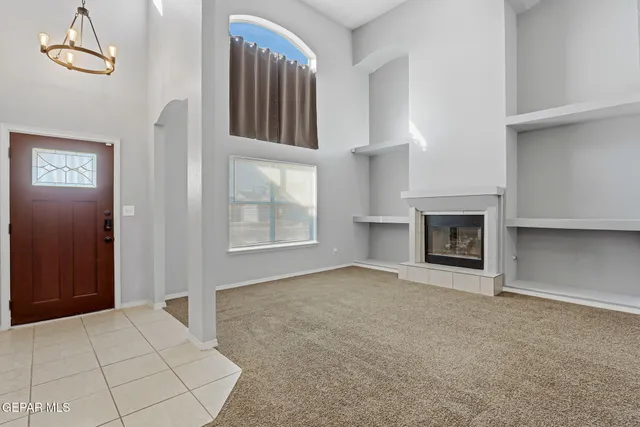 a view of a dining room and livingroom with furniture wooden floor a rug a painting and a chandelier